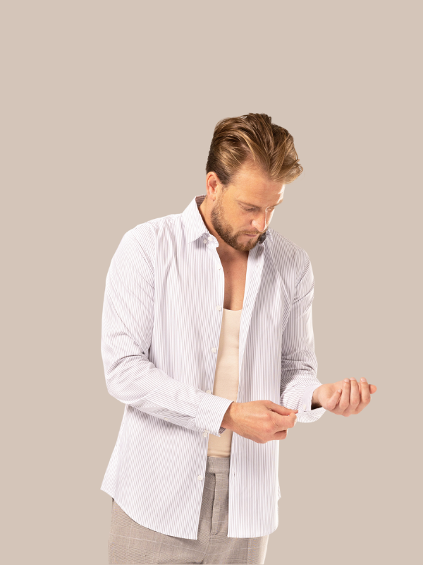 Male adjusting shirt cuff getting changed with shirt on over his nude undershirt